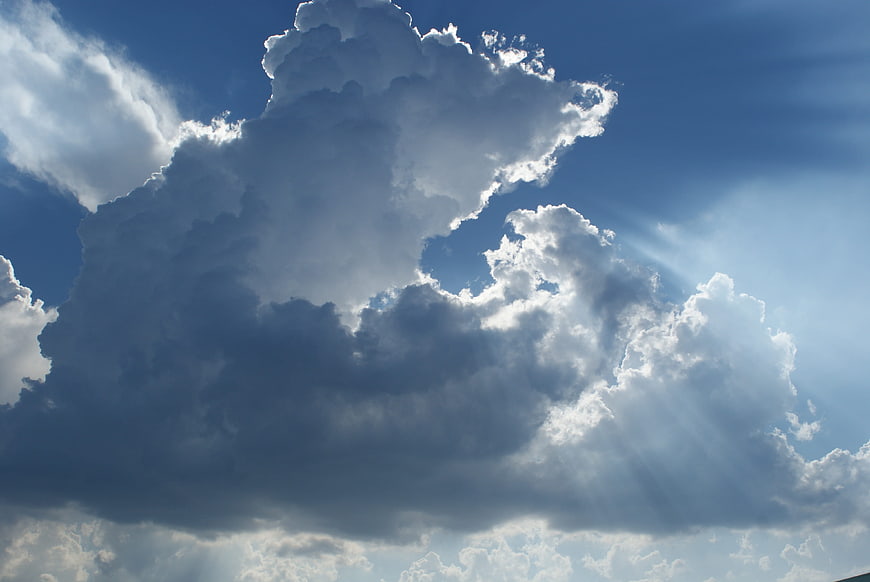 Dramatic cumulus clouds with sun rays in blue sky