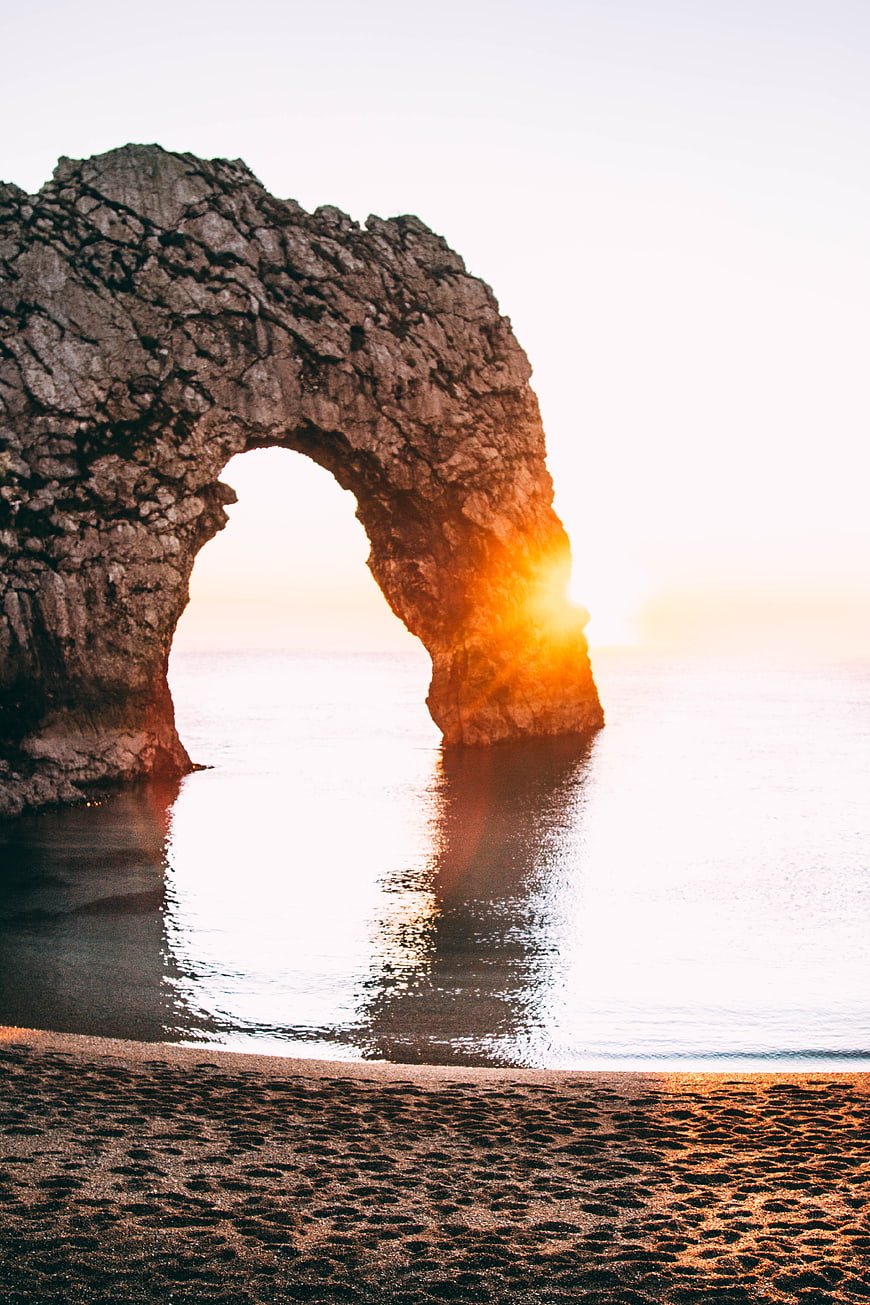 Sunset Through Natural Rock Arch on Sandy Beach