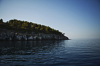 Serene Coastal Landscape with Rocky Cliff and Pine Trees