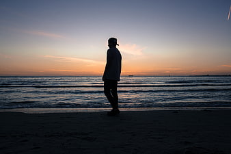 Silhouette of Man Standing on Beach at Sunset