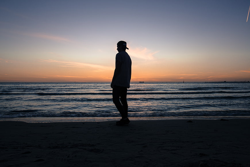 Silhouette of Man Standing on Beach at Sunset