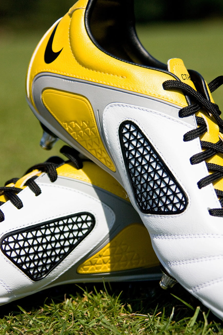 Close-up of yellow and white soccer cleats on grass