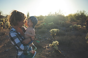Mother holding baby in desert landscape at golden hour