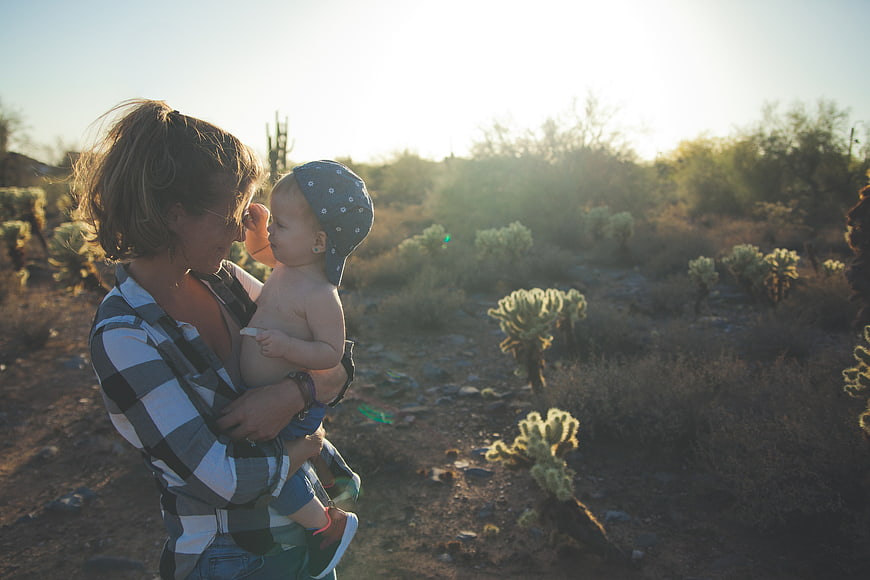 Mother holding baby in desert landscape at golden hour
