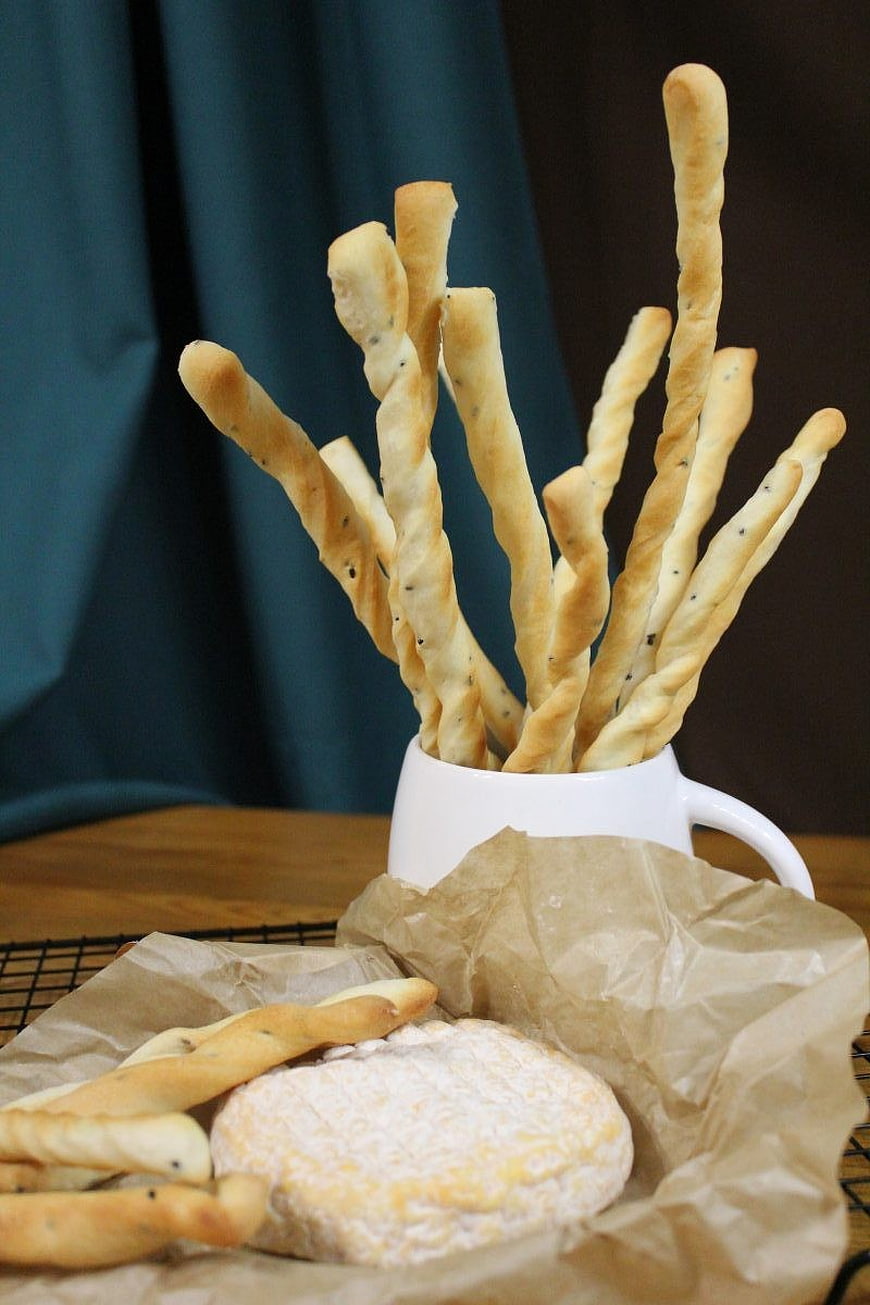 Grissini breadsticks and soft cheese on parchment paper