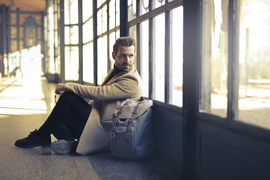Handsome man sitting by window with backpack waiting