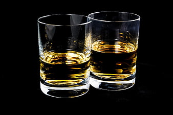 Two glasses of amber whiskey on a black background