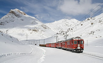 Red Train Traveling Through Snowy Mountain Pass