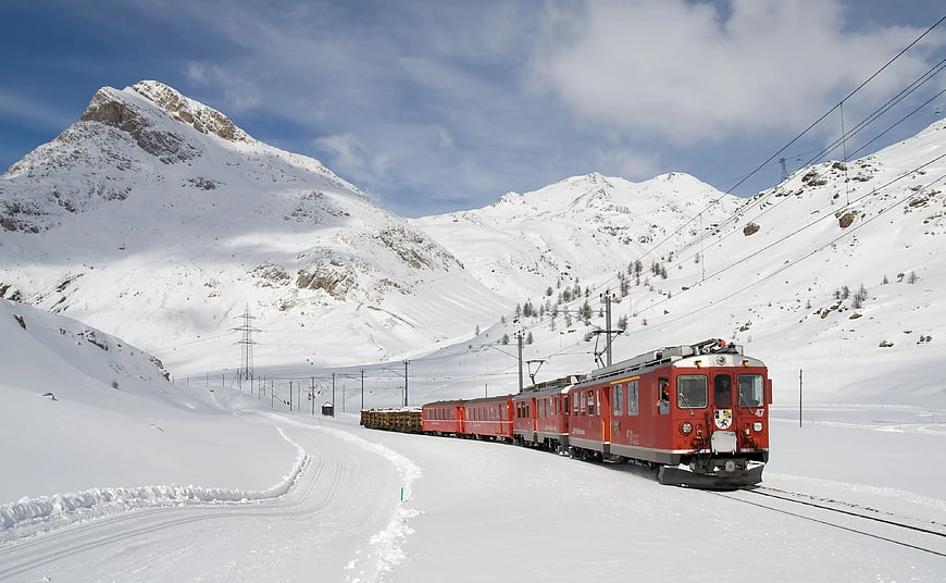 Red Train Traveling Through Snowy Mountain Pass