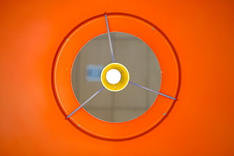 Orange circular lamp shade with yellow bulb and metal supports