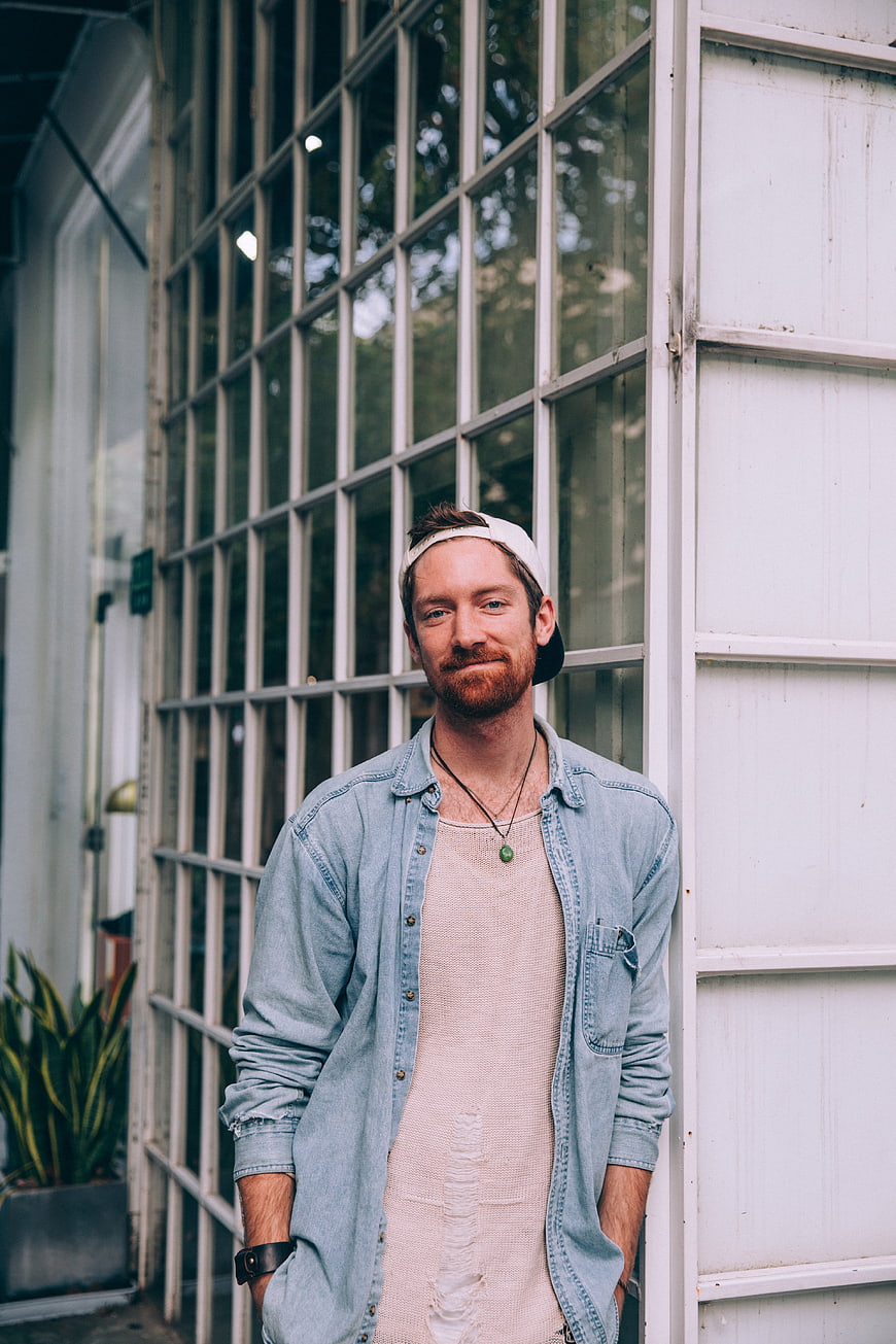 Casual man with beard and cap standing by window