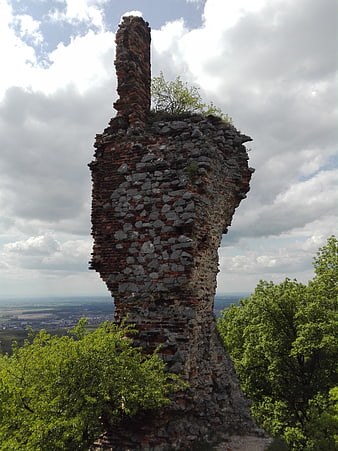 Ancient stone and brick castle ruin tower against cloudy sky