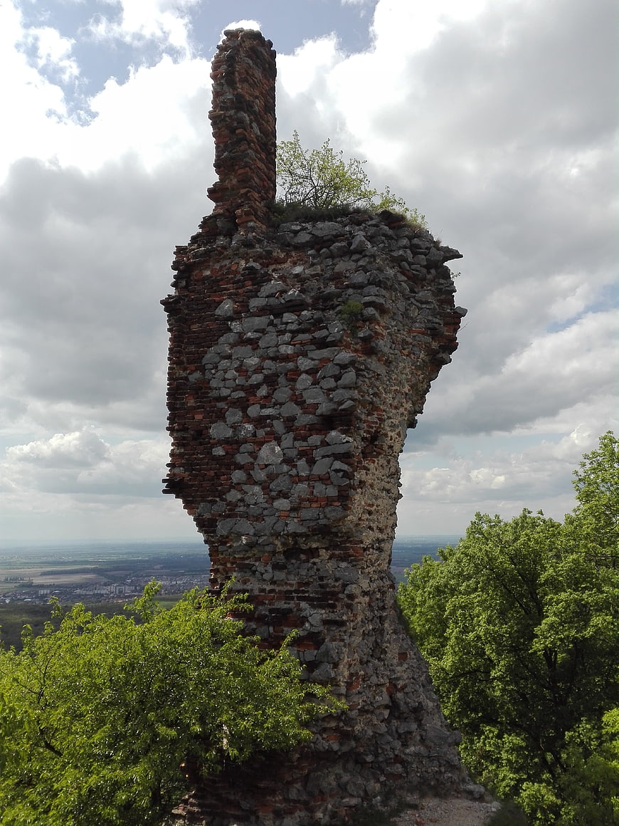 Ancient stone and brick castle ruin tower against cloudy sky