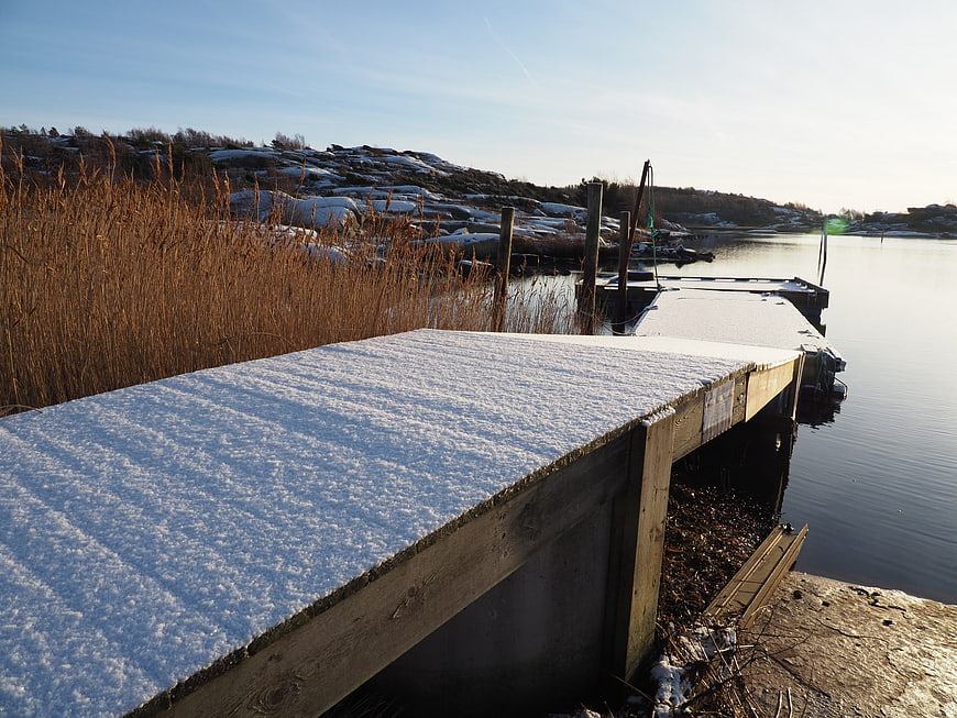 Snow-covered wooden dock by calm winter water
