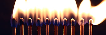 Row of burning matchsticks with bright flames on black background