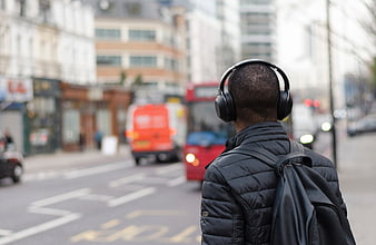 Man with headphones and backpack on busy city street