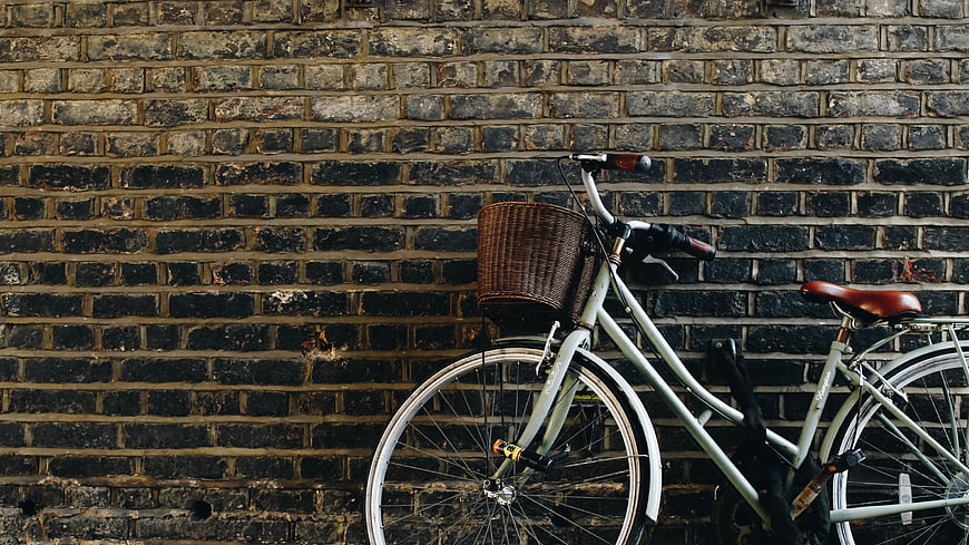 Vintage bicycle with basket against dark brick wall