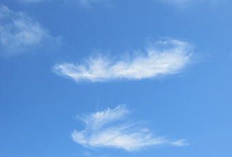 Wispy white clouds against a clear blue sky background