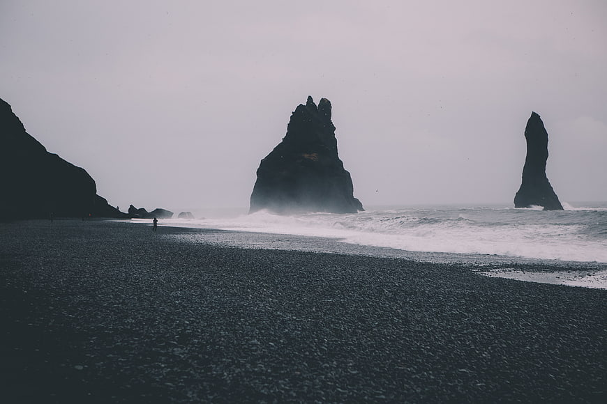 Dramatic black sand beach with sea stacks and crashing waves
