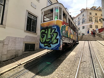 Colorful Graffiti Tram on Cobblestone Street in Lisbon