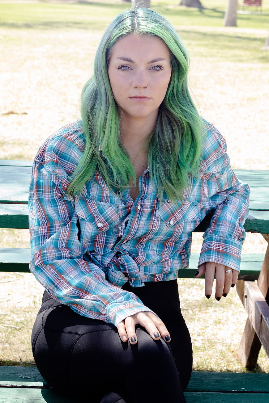 Young Woman with Green Hair Sitting on Park Bench
