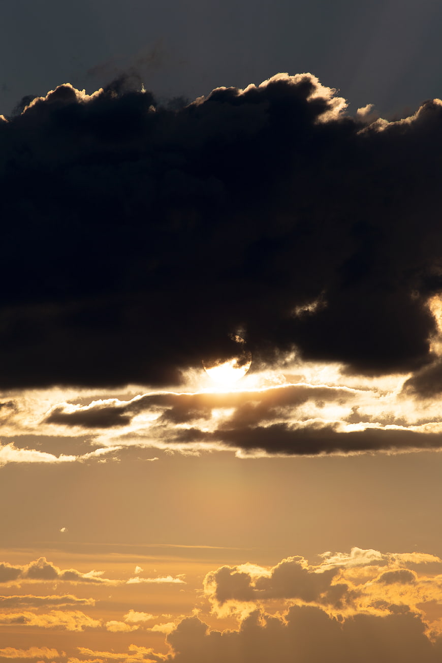 Dramatic sunset with sun breaking through dark storm clouds