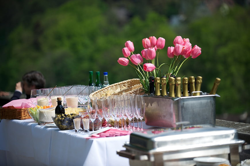 Outdoor catering table with champagne and pink tulips