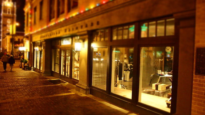 Nighttime street view of illuminated boutique storefronts with couple walking