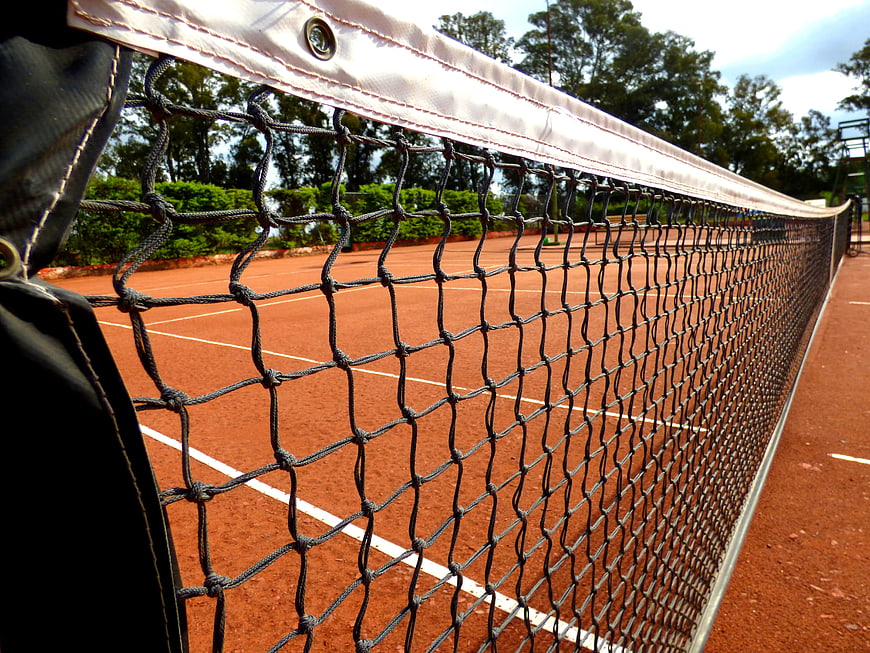 Close-up of tennis net on a red clay court