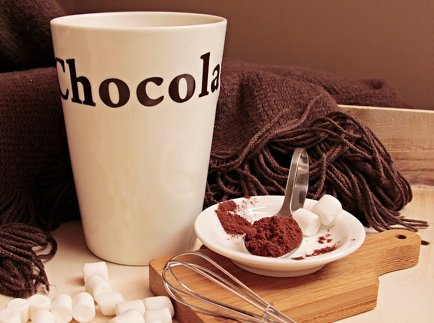 Cozy Hot Chocolate Setup With Cocoa Powder, Marshmallows, And Whisk