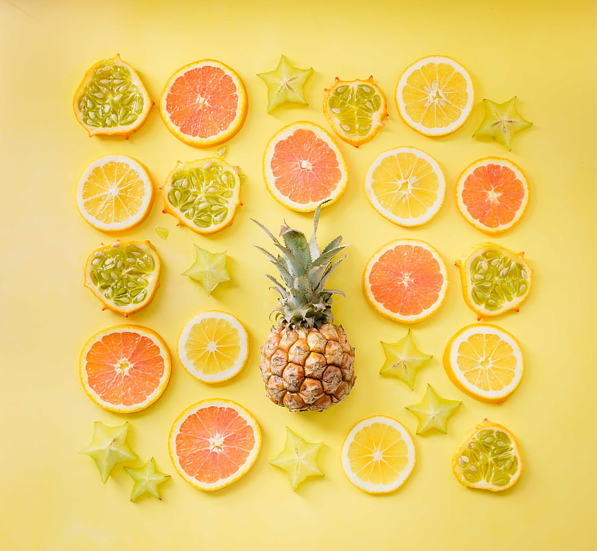 Flat lay of sliced citrus fruits and pineapple on yellow background