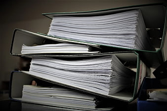 Stack of overflowing office binders with paperwork