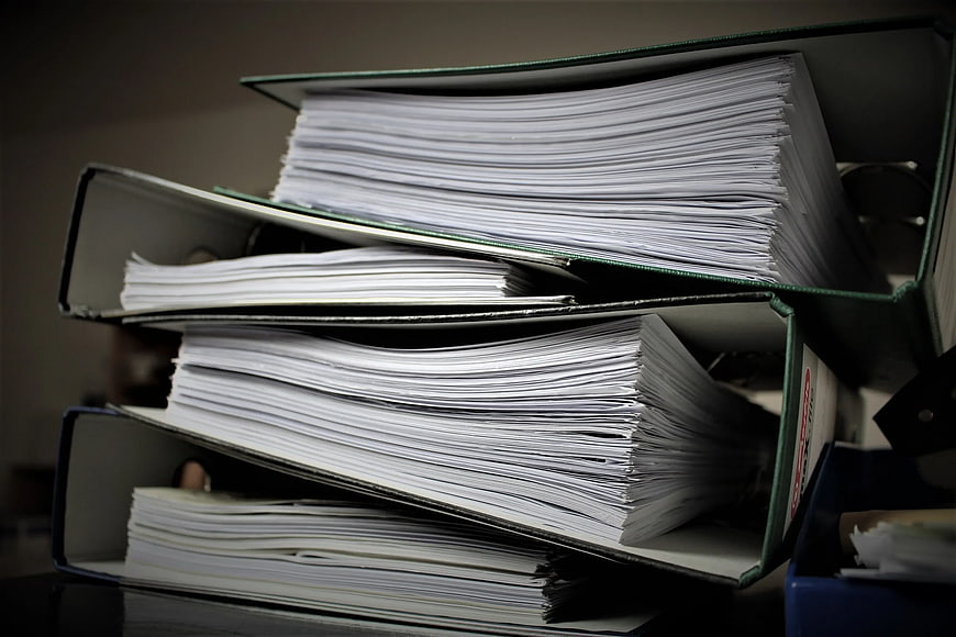 Stack of overflowing office binders with paperwork