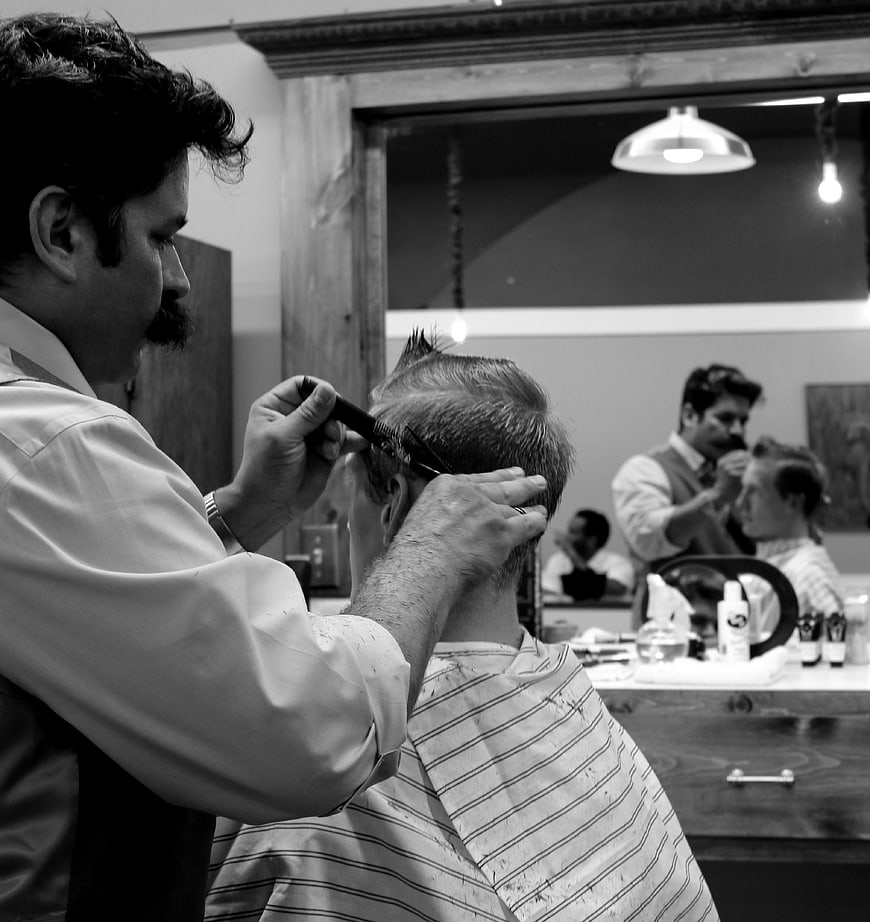 Barber cutting hair in vintage black and white salon