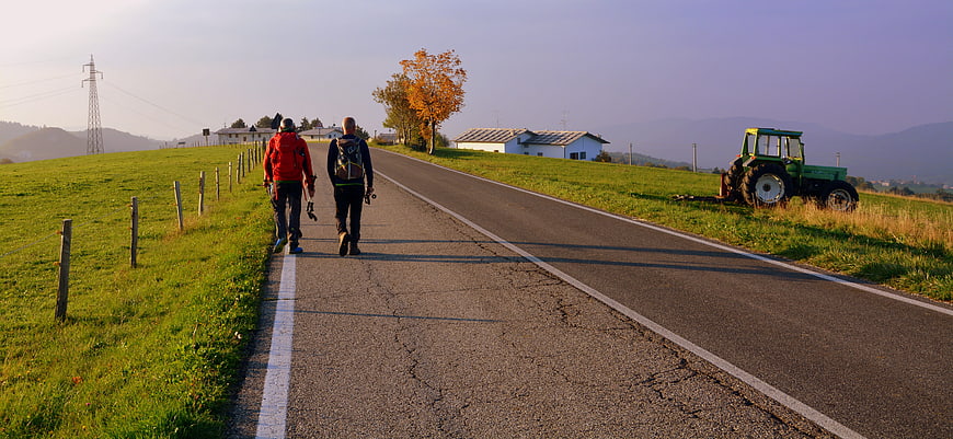 Two Hikers Walking on Country Road with Tractor