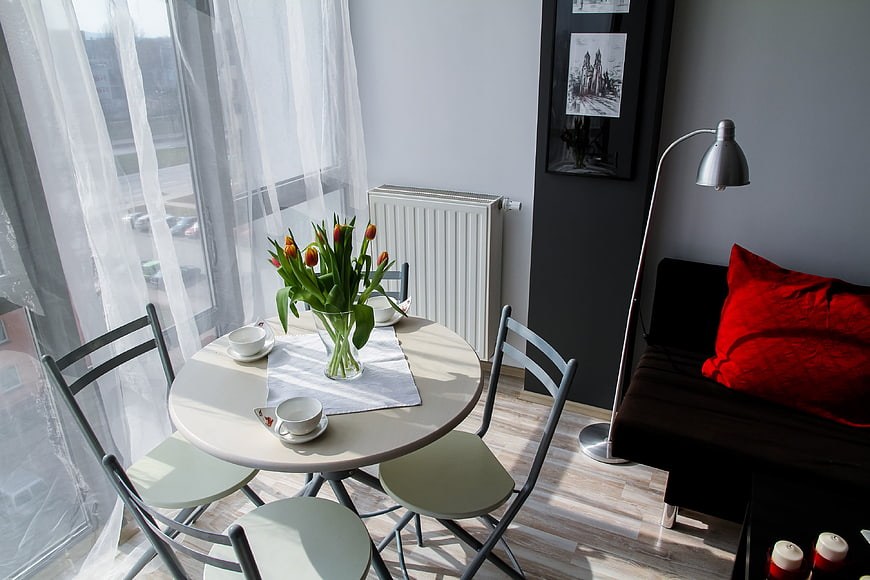 Bright apartment dining area with tulips and red pillow