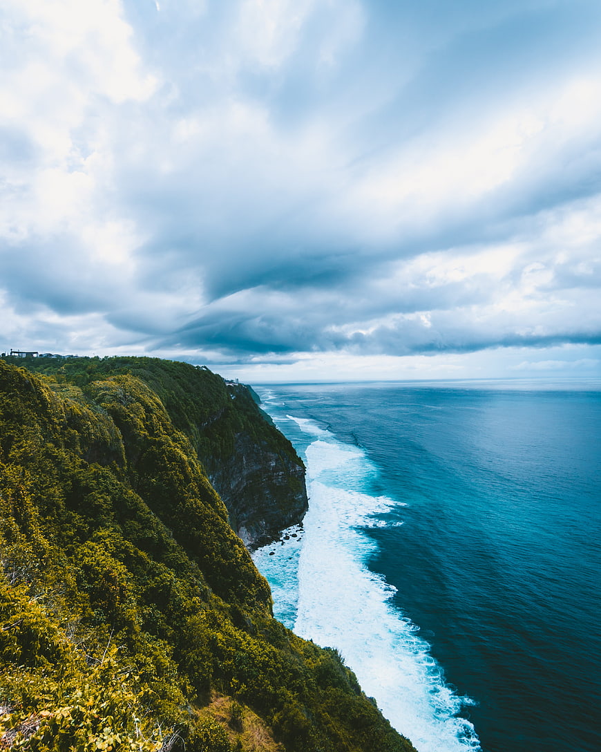 Dramatic Aerial View of Lush Green Coastal Cliffs and Turquoise Ocean
