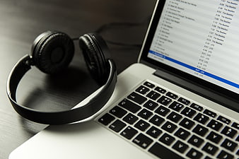Black headphones resting on a silver laptop keyboard