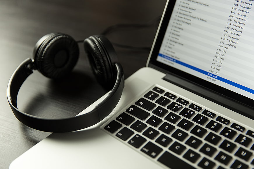 Black headphones resting on a silver laptop keyboard