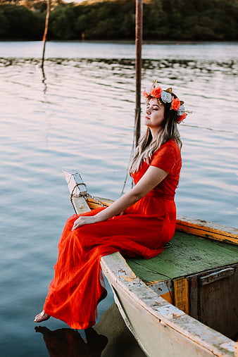Woman in Red Dress with Flower Crown Sitting on Boat