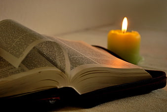 Open Bible with Lit Candle on Table