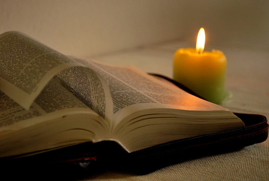 Open Bible with Lit Candle on Table