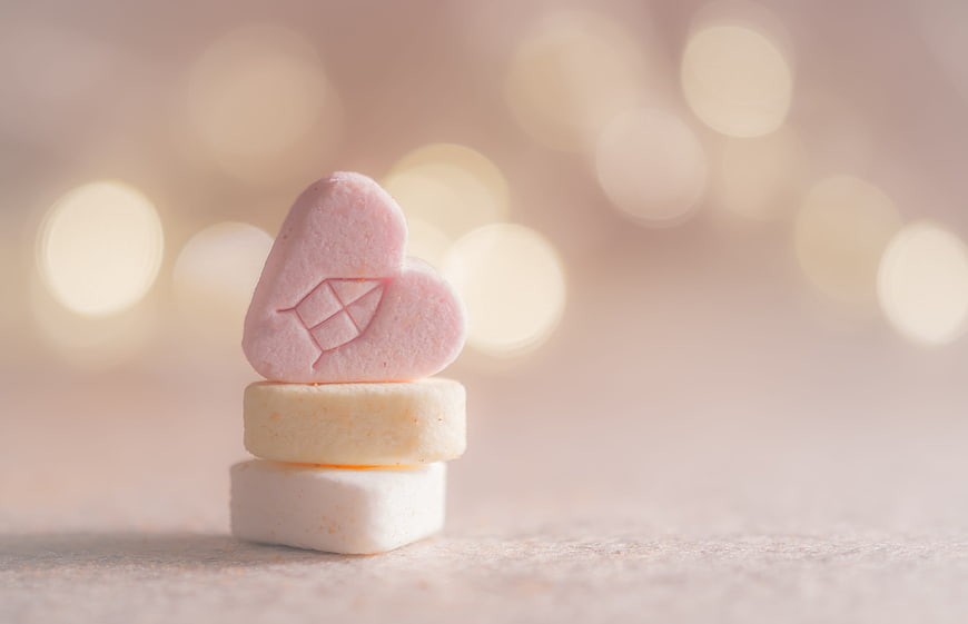 Stacked pink heart and white marshmallows with warm bokeh background