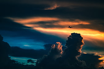 Silhouette of Airplane Flying Through Dramatic Sunset Clouds