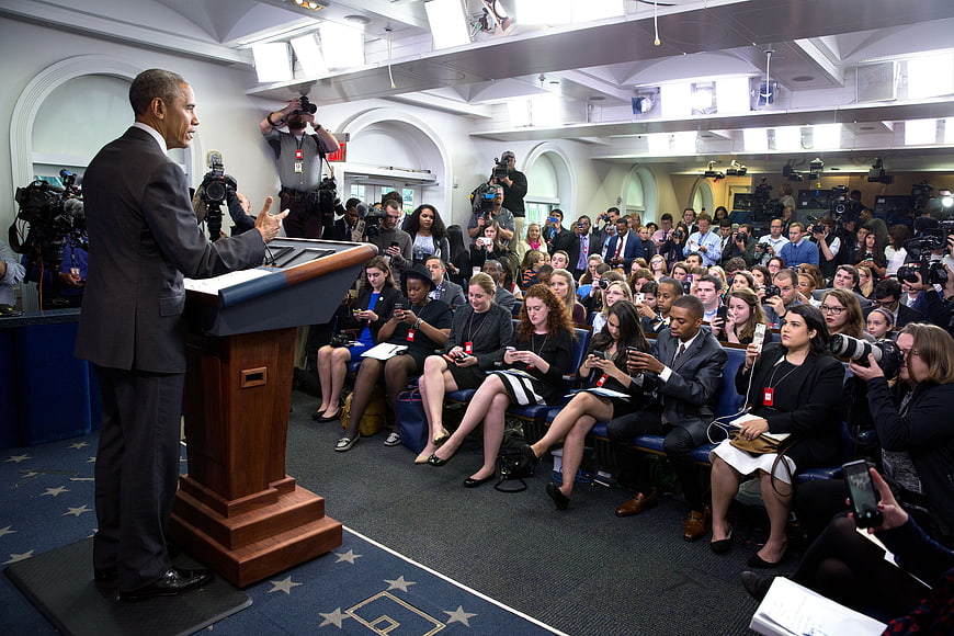 President Obama speaking at a press conference to a crowd of journalists