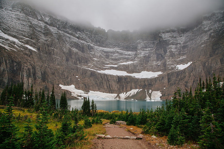 Misty Mountain Lake with Snowy Cliffs and Forest Trail