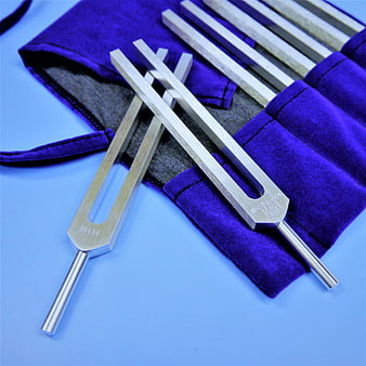 Metal tuning forks and metal rods in purple velvet case