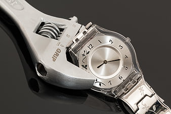 Silver Wristwatch Held By Adjustable Wrench On Black Background