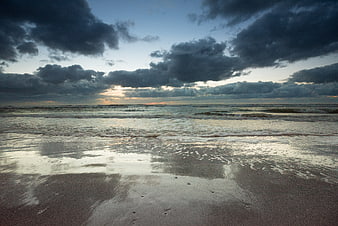 Dramatic storm clouds over ocean waves at sunset