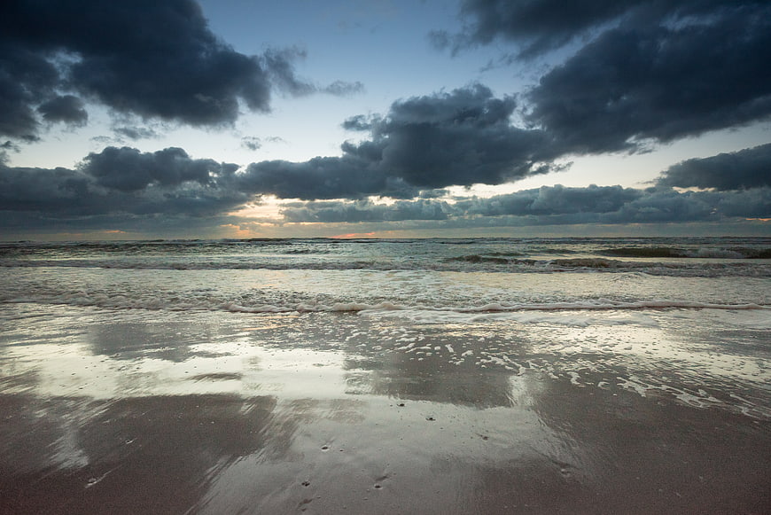 Dramatic storm clouds over ocean waves at sunset